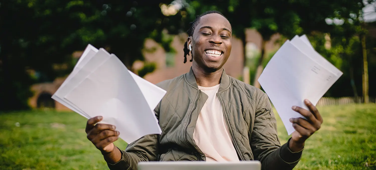 Student smiling holding papers