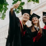 Three students wearing graduate gowns