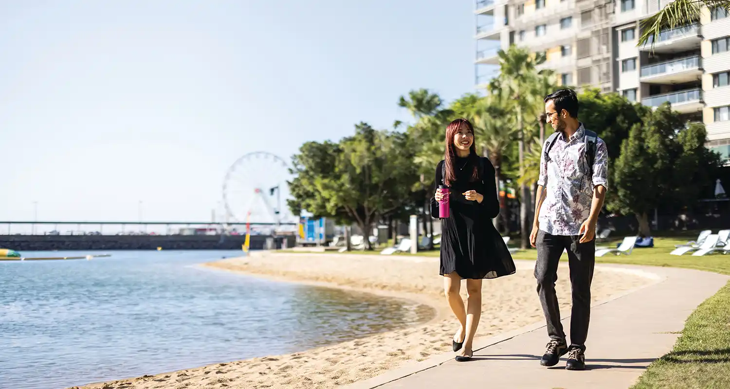Two people walking along waterfront path
