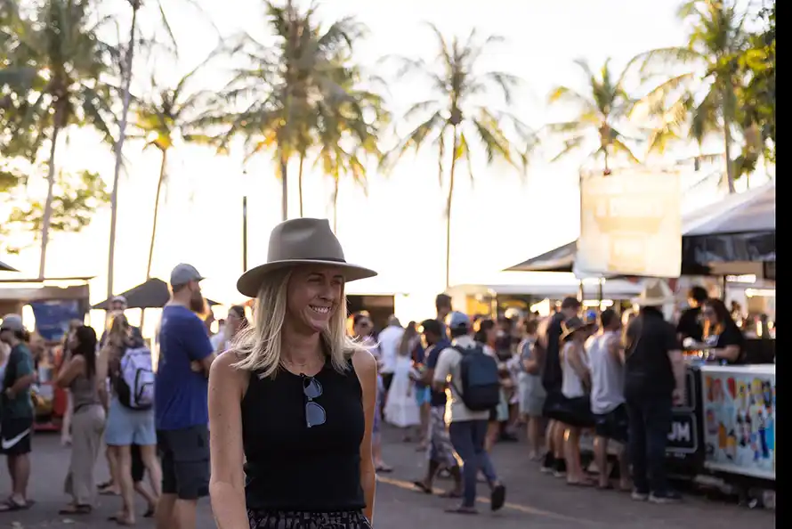 Lady wearing a hat walking through an outdoor market in sunshine