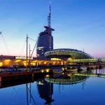 Buildings illuminated at night time next to a body of water