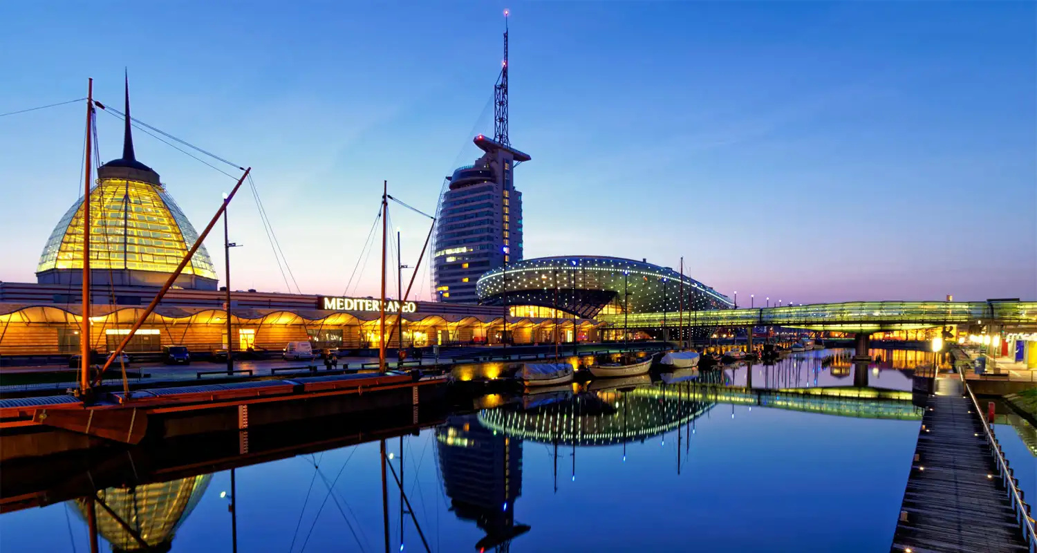 Buildings illuminated at night time next to a body of water