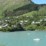 Village located next to body of water with green hill in the background