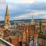 Image of Dundee's skyline, with an old church spire and other old red brick buildings