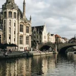 Concrete building next to river with a bridge going over