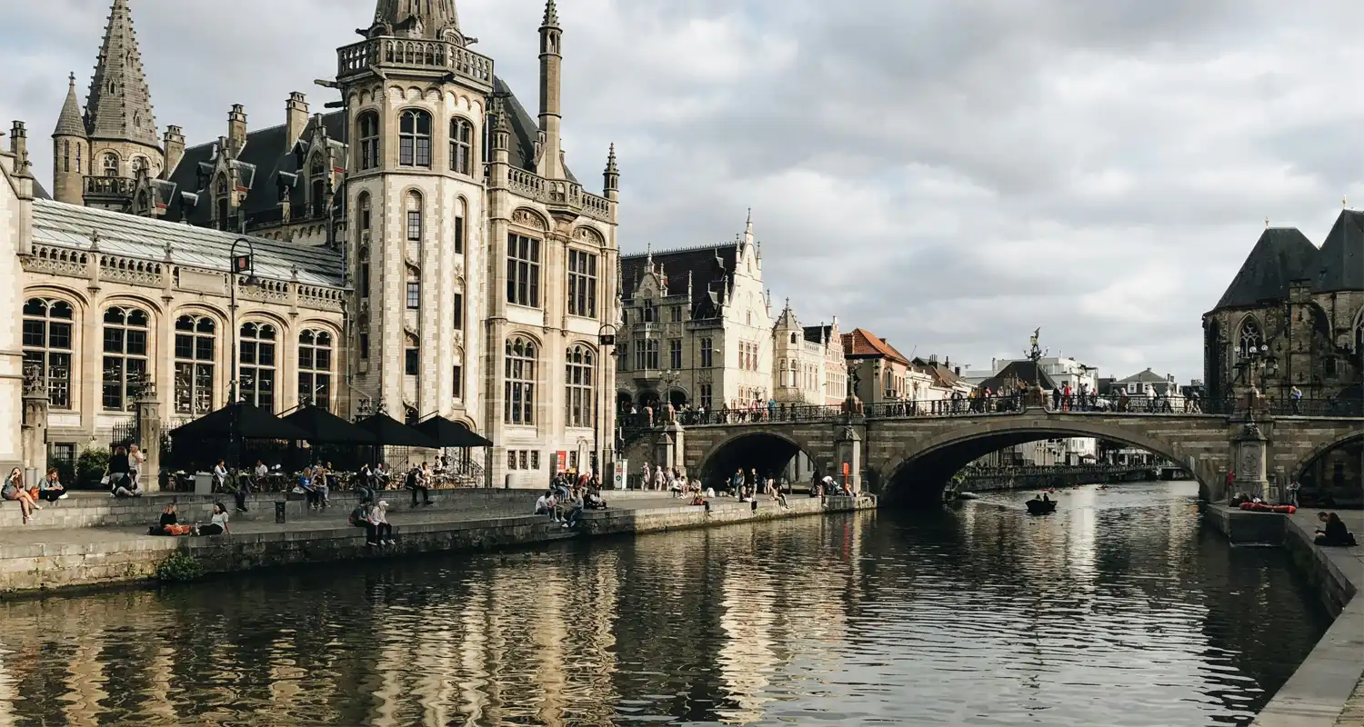 Concrete building next to river with a bridge going over