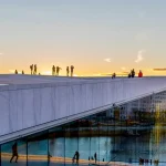 Image of people stood on the roof of a building with a sunset in the background
