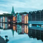 Image of buildings next to a river with trees in the background