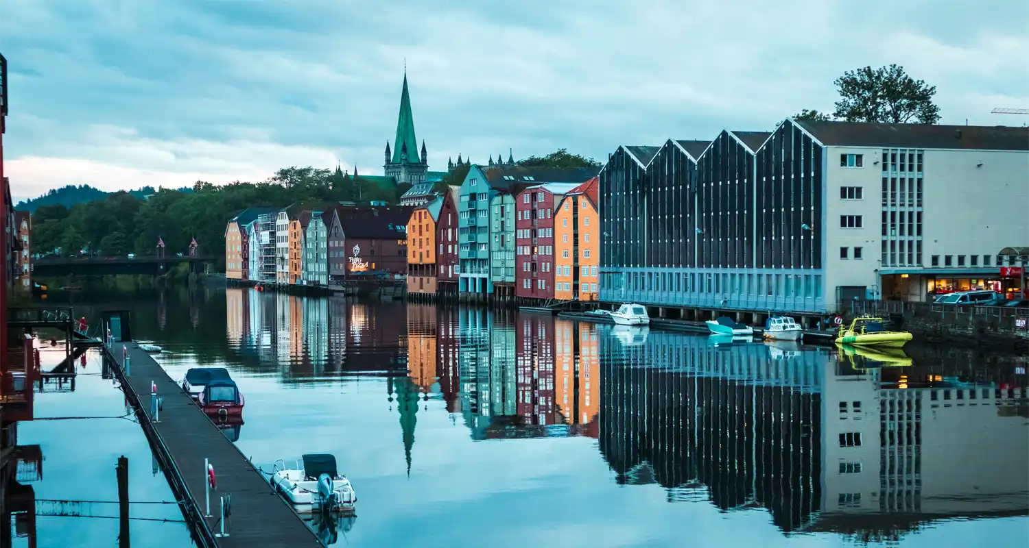 Image of buildings next to a river with trees in the background