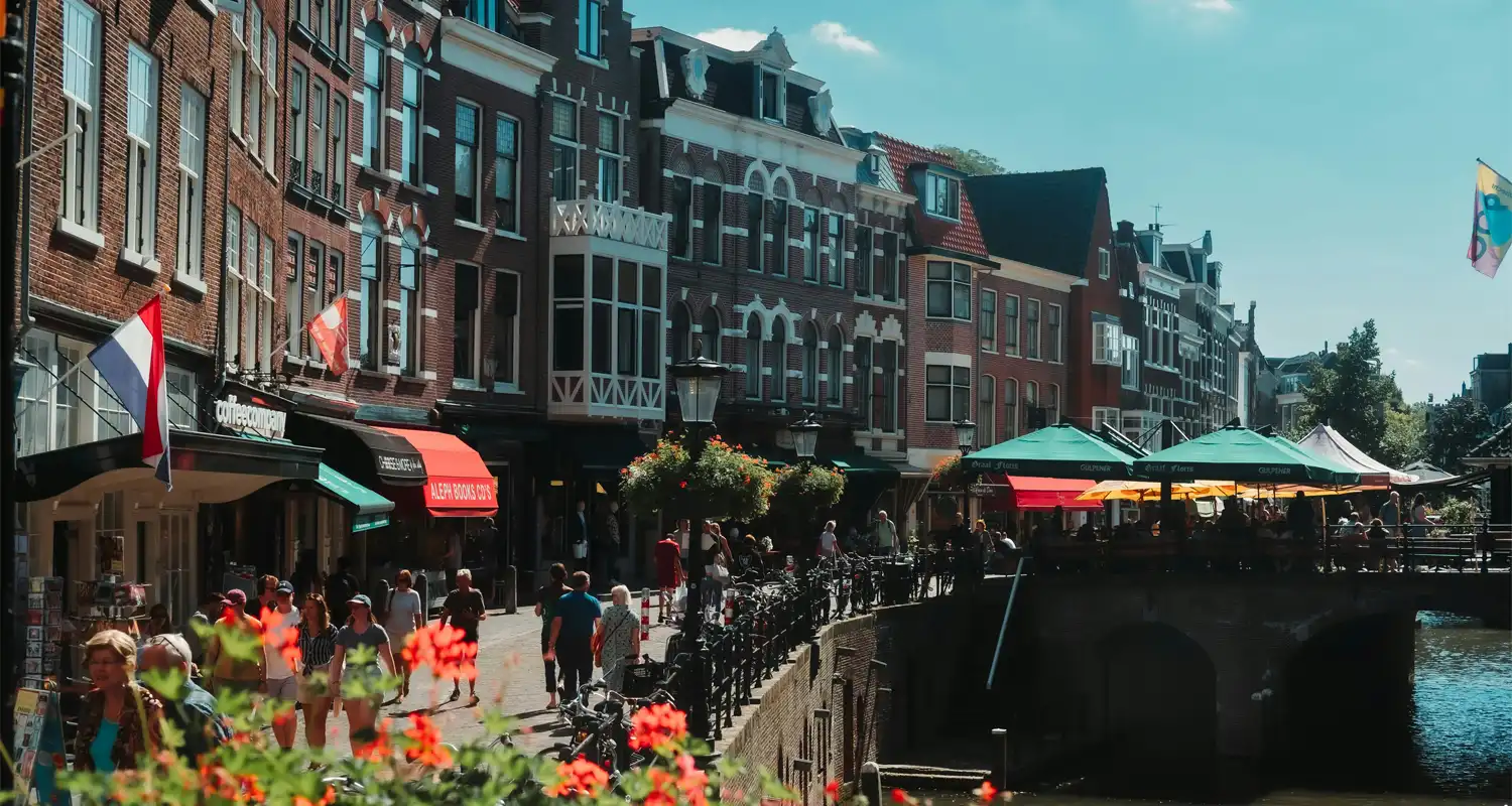 Image of a canal with buildings and people walking next to it
