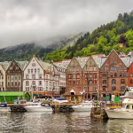 Several boats docked up by a row of traditional buildings