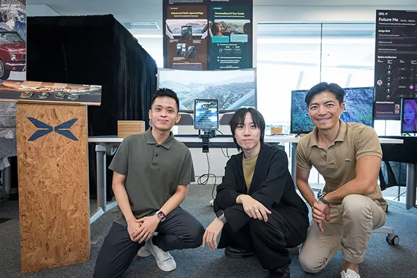 Three students kneeling next to each other and smiling at the camera.