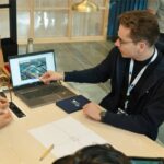 Students sat around a table all looking at a laptop screen