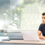 Image of a student sitting at a table with their laptop open in front of them