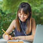 Lady writing notes next to laptop