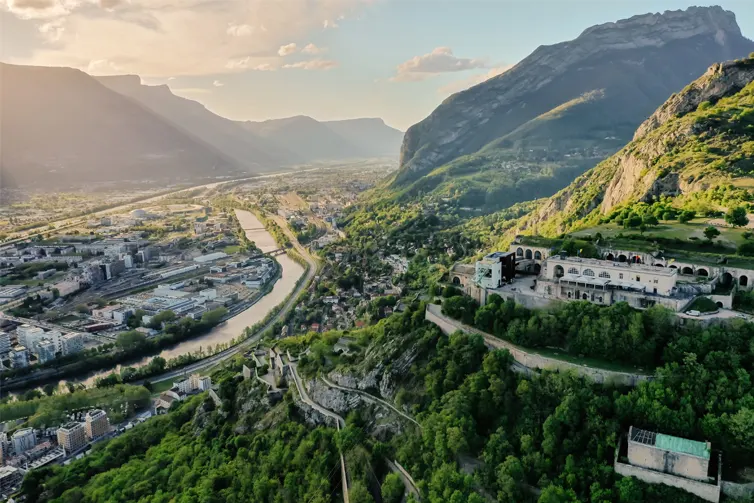 A city in the bottom of a valley surrounded by lush green mountains