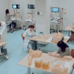 Image of students standing at tables with cpr dummies on them