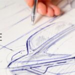 Image of a person's hand drawing a picture of a car with a blue pen