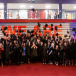 Students wearing graduation gowns, throwing their graduation caps in the air