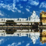 White and gold temple style building with a body of water in front of it