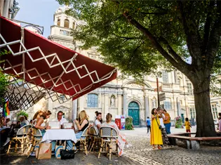 People sat at a restaurant table in a cobbled square