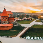 An aerial photo of a castle with a red roof by a body of water