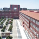 Image of a long red brick building next to a green space