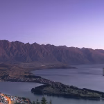 A aerial photograph of a glass building with a beautiful view over a body of water