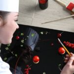 Student using food to decorate a large black plate