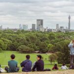 Image of a group of people sitting on grass at the top of a hill