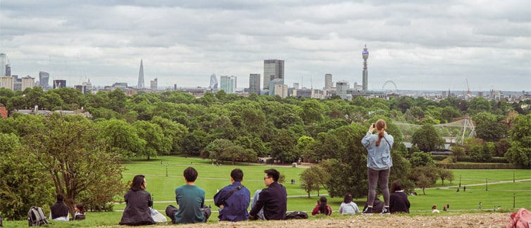 Image of a group of people sitting on grass at the top of a hill