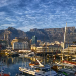 A boat harbour by a body of water with a mountain in the background
