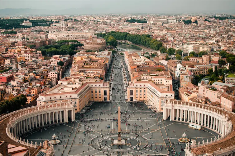 Birds eye view of a city, with people walking in a city square surrounded by columns.