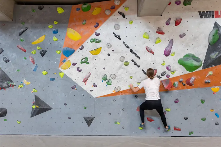 Image of a student on a climbing wall, about a foot off of the ground