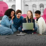 Four students looking at a laptop and laughing together