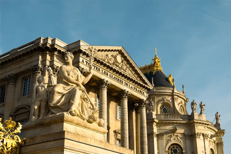 Large sandstone building with a statue in front of it
